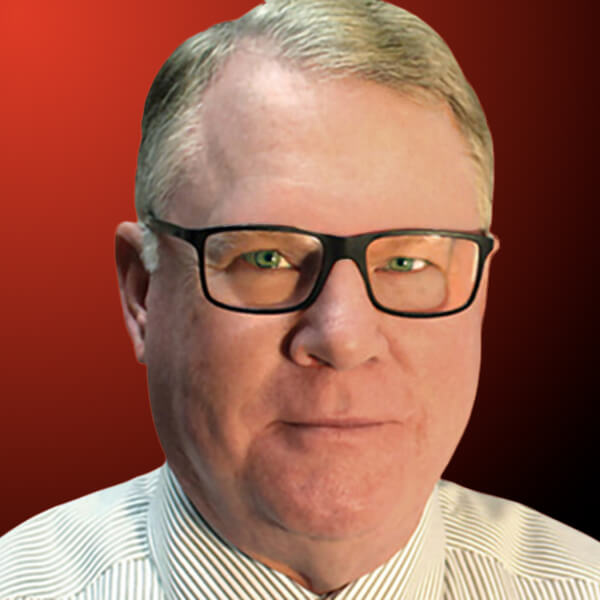 Professional headshot of a man wearing glasses with short light hair against an orange to black gradient background.