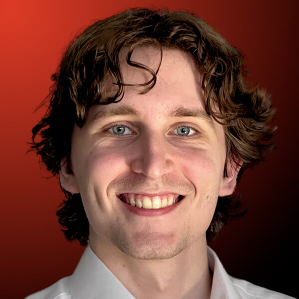 Professional headshot of a smiling man with wavy hair against an orange to black gradient background.