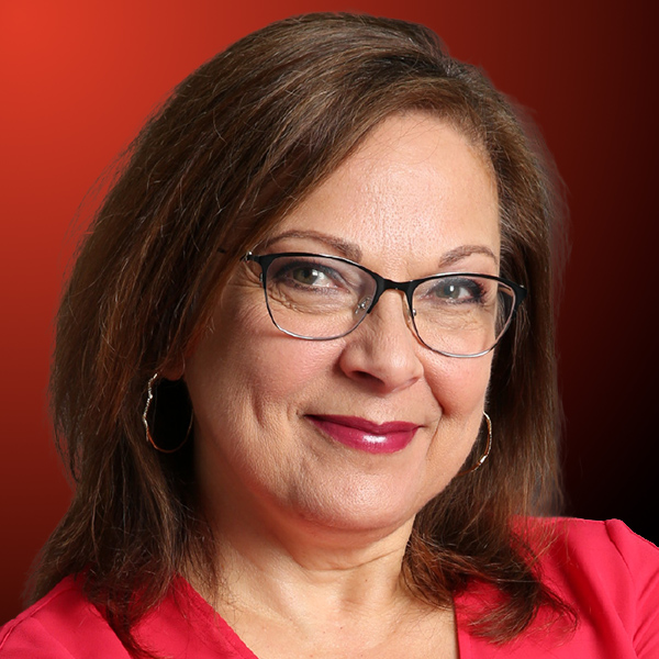 Professional headshot of a smiling woman with brown hair against an orange to black gradient background.