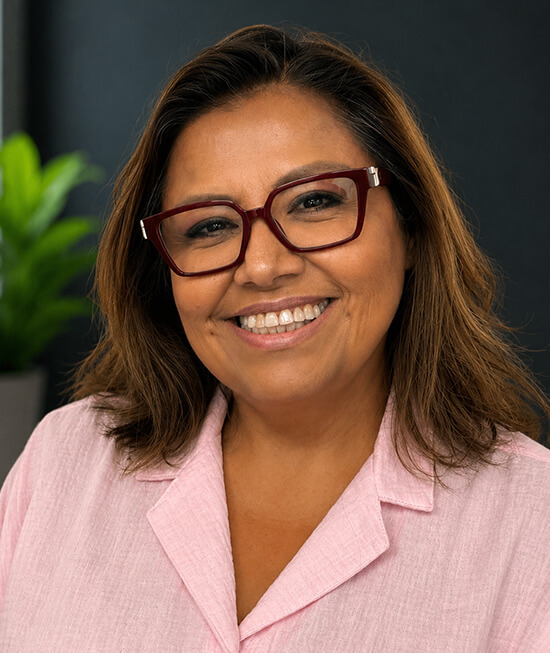 Professional headshot of a smiling hispanic woman with dark hair wearing a pink shirt.