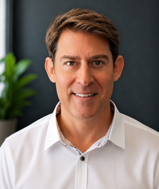 Professional headshot of a man with short hair wearing a white shirt.