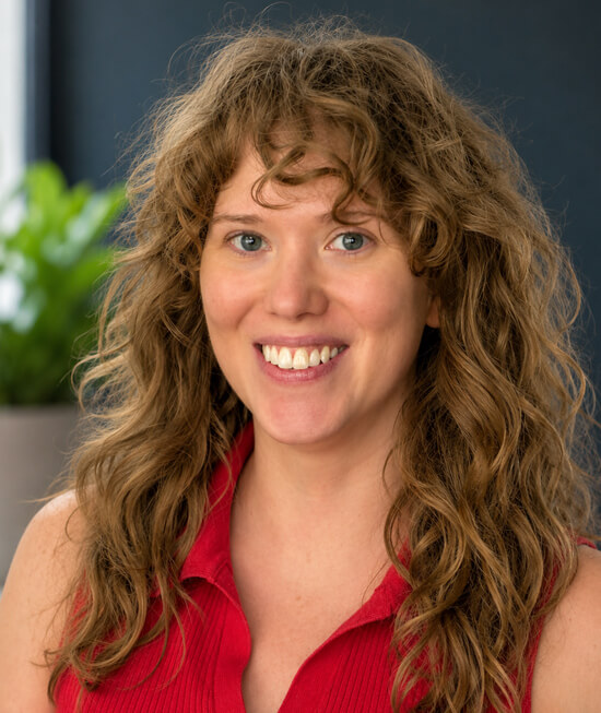 Professional headshot of woman with curly hair wearing a red shirt.